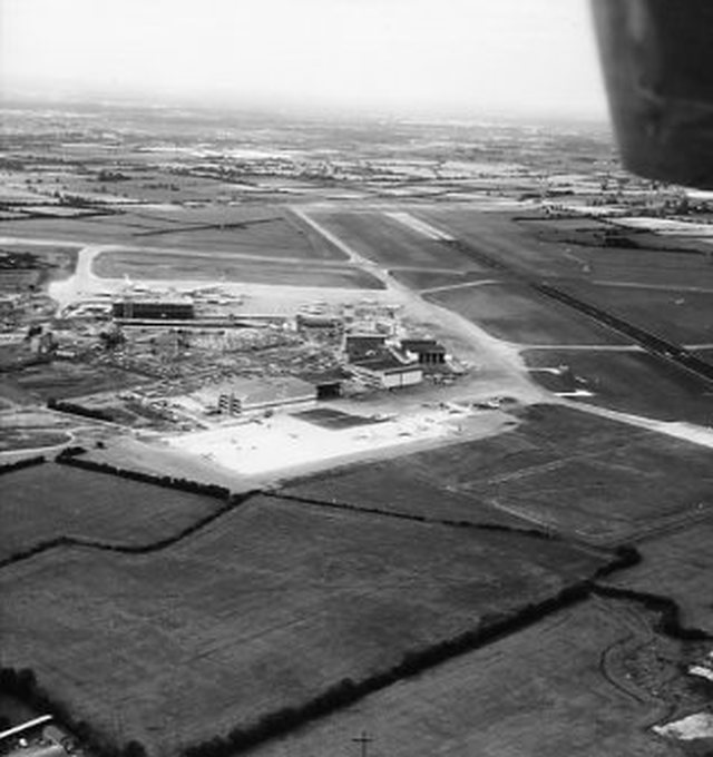 Aerial black-and-white view of Cambridge Airport's runway and hangars