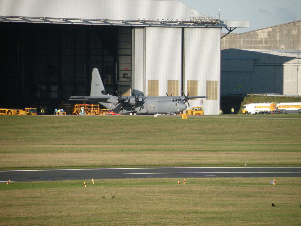 Mechanics maintaining a wartime aircraft in a historic hangar